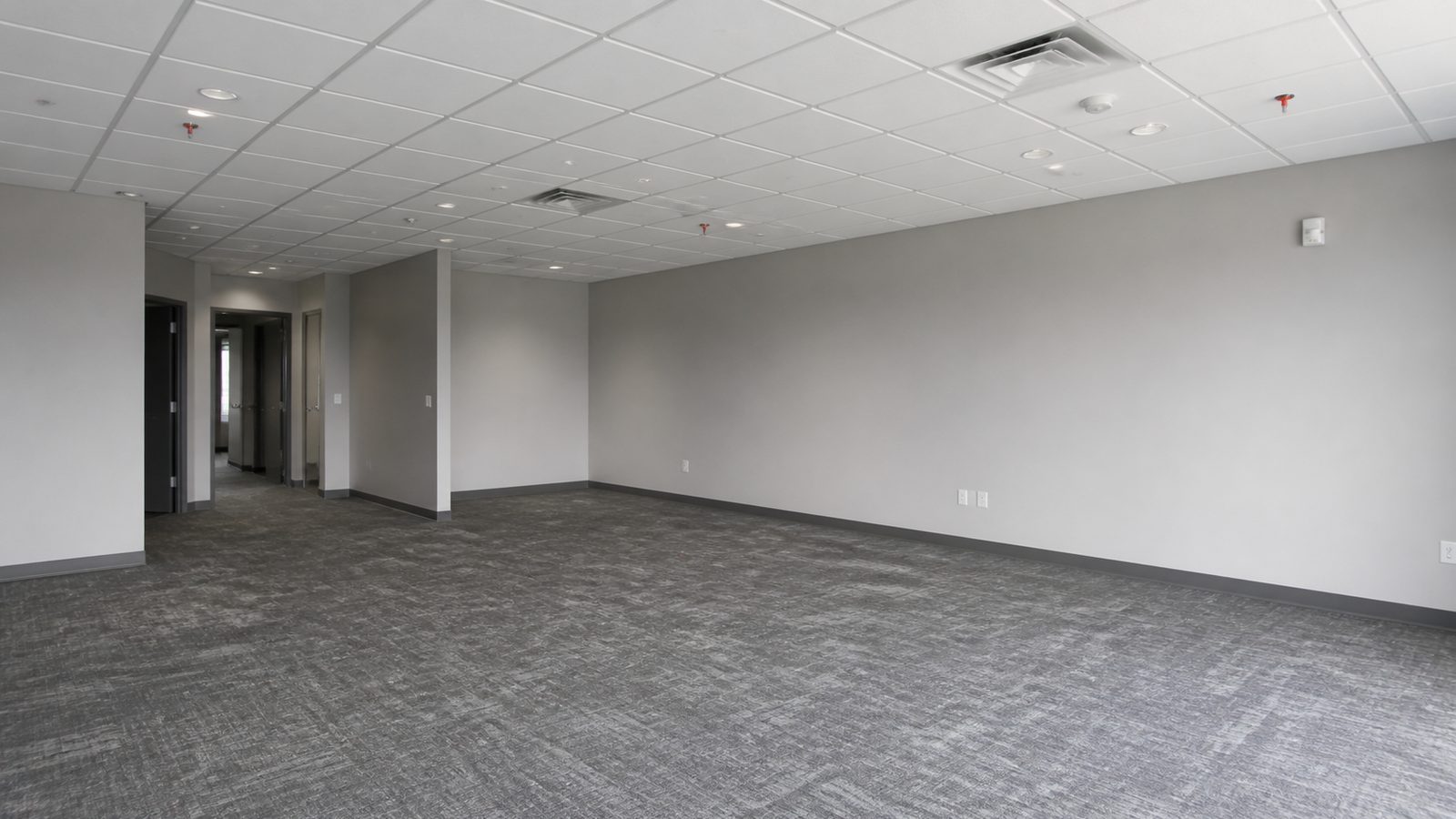 Empty finished commercial suite with aligned ceiling systems and clear floor transitions