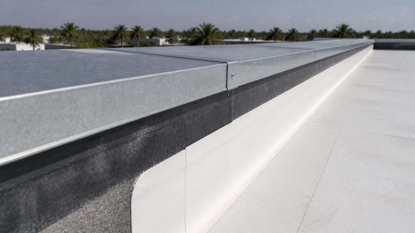 Galvanized parapet coping cap with a tight lap joint above a white commercial roof membrane