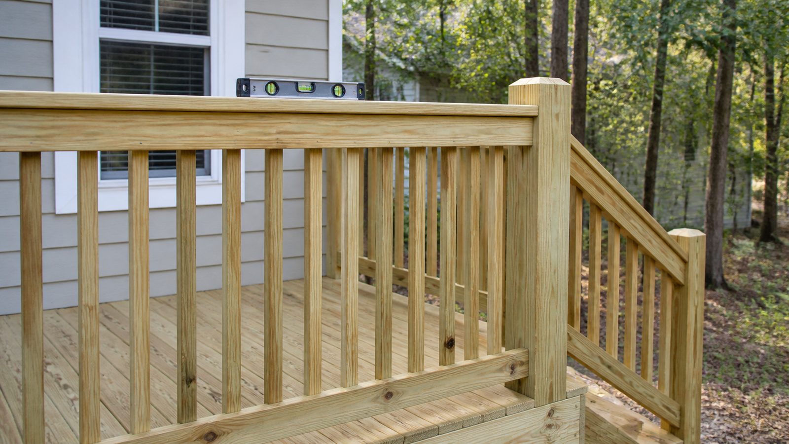 Pressure-treated deck guardrail with straight top rail, even balusters, and a level