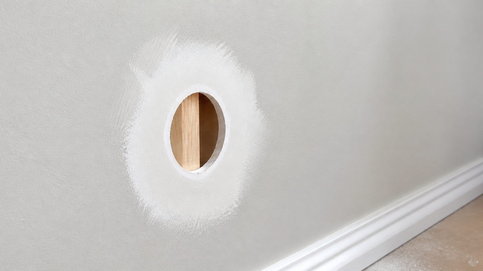 Small drywall opening prepared with a backing strip and feathered joint compound