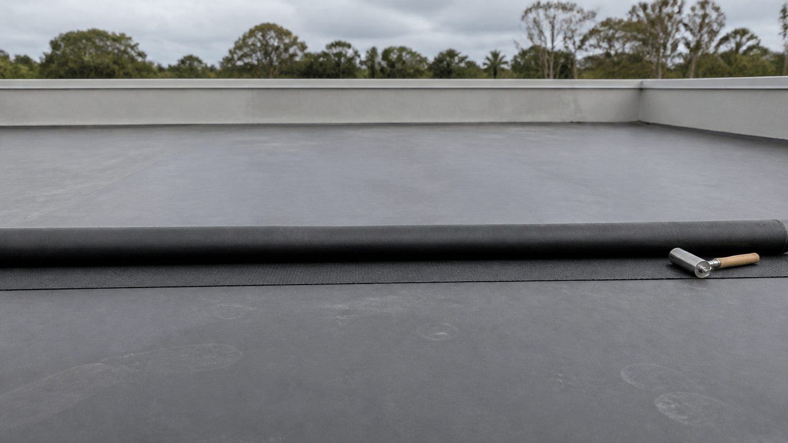 Black EPDM overlap prepared beside a plain seam roller