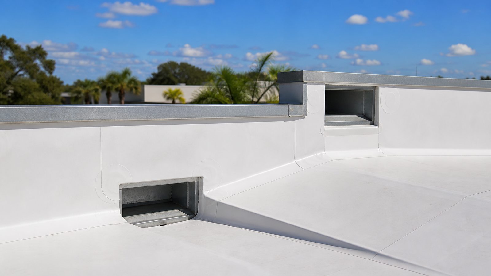 TPO roof parapet with separate primary and emergency overflow scuppers