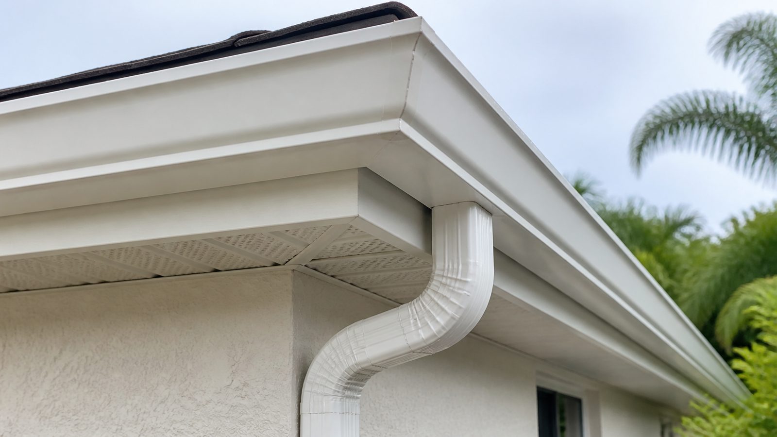 White gutter corner and downspout transition at a Florida stucco home