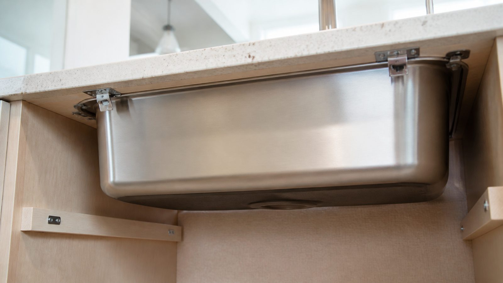 Underside of a kitchen counter showing sink support clips and a clean drain opening