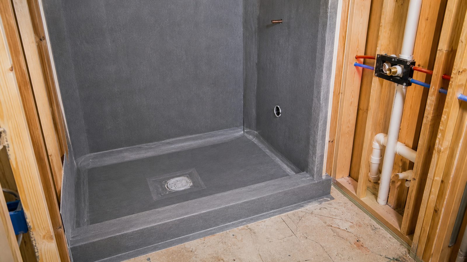 Master bathroom shower under construction with continuous waterproofing membrane, recessed niche, drain, and carefully prepared wall framing