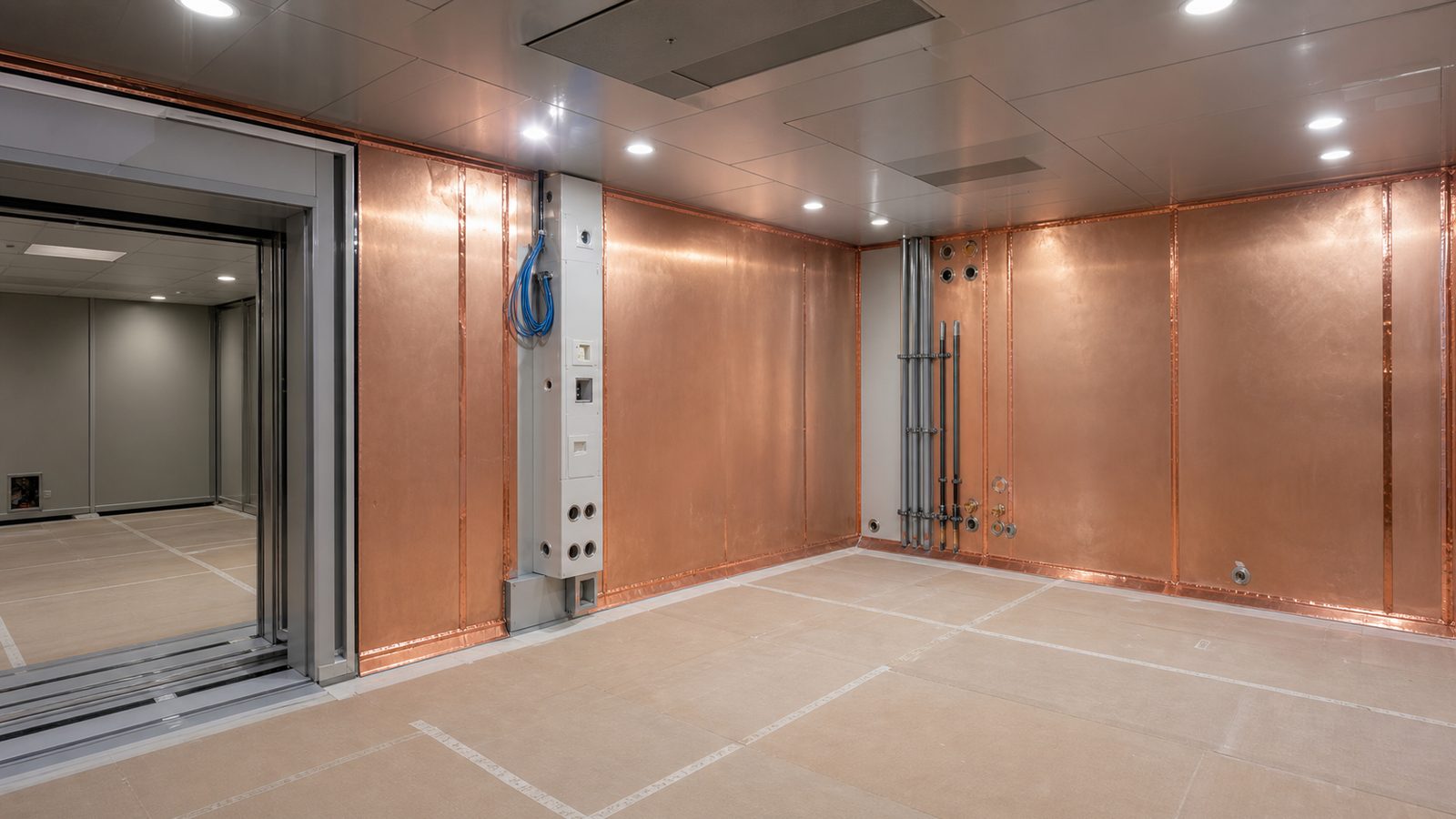 MRI suite under specialist construction with copper RF shielding panels, equipment doorway, protected floor, and service penetrations