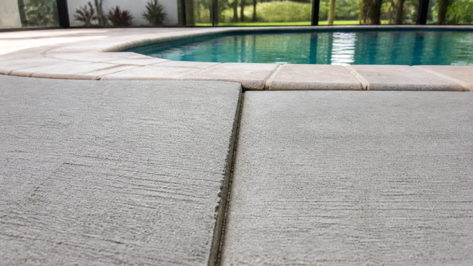 Pool-deck slab sections with a subtle vertical offset from settlement beside the coping
