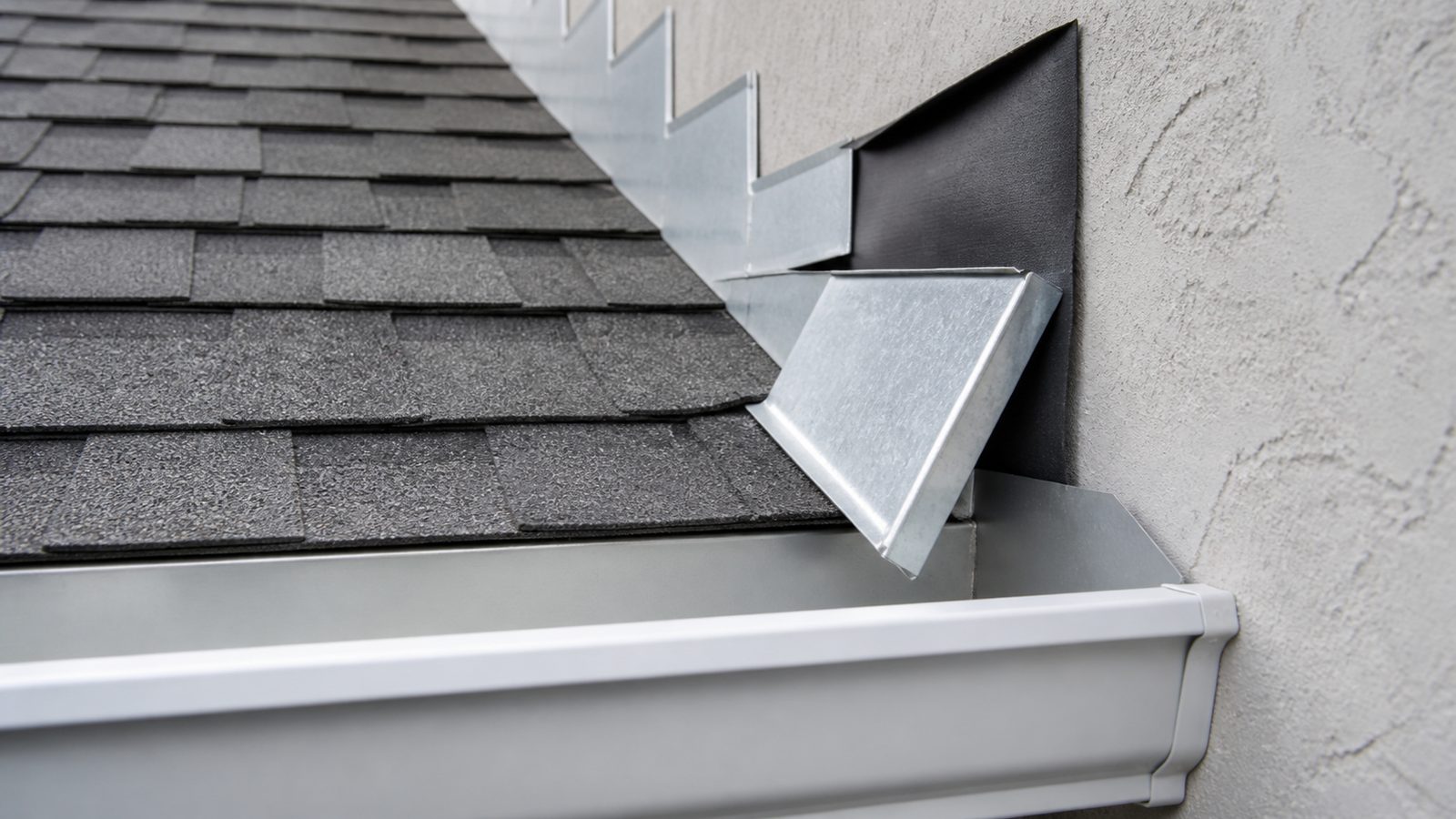 Galvanized kickout flashing directing a shingle roof edge into a white gutter