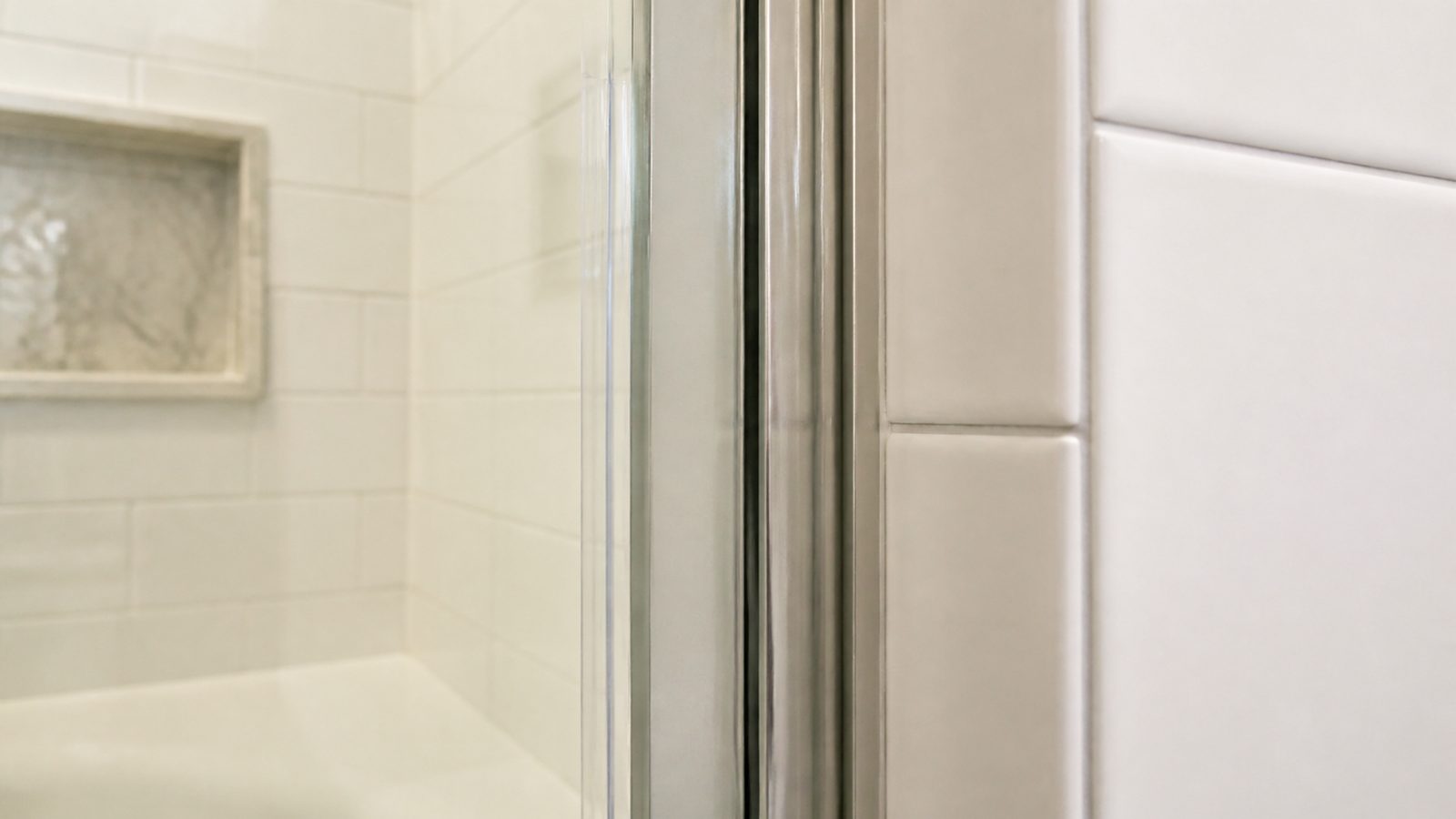 Clear shower-door side seal meeting an even tiled jamb gap