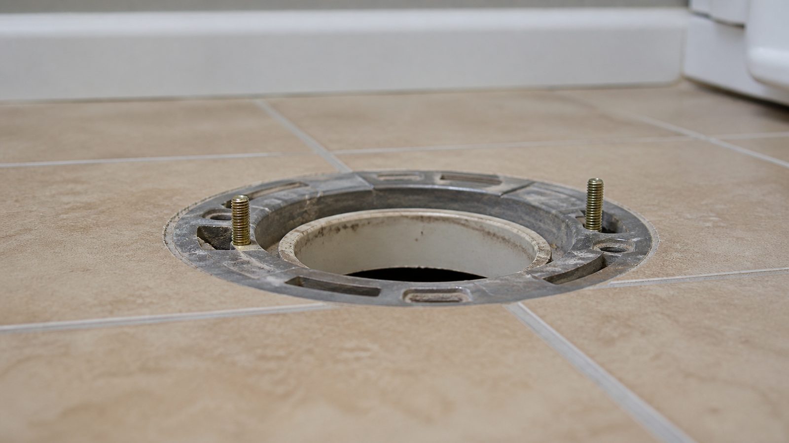 Bathroom floor opening showing a flange set below finished floor height