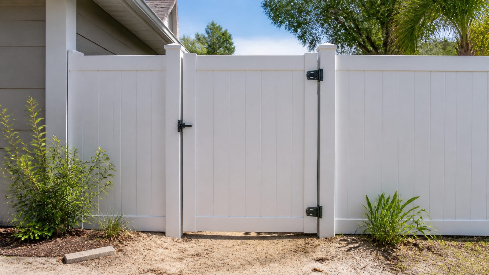 White vinyl fence gate aligned squarely between two posts with black hinges and latch