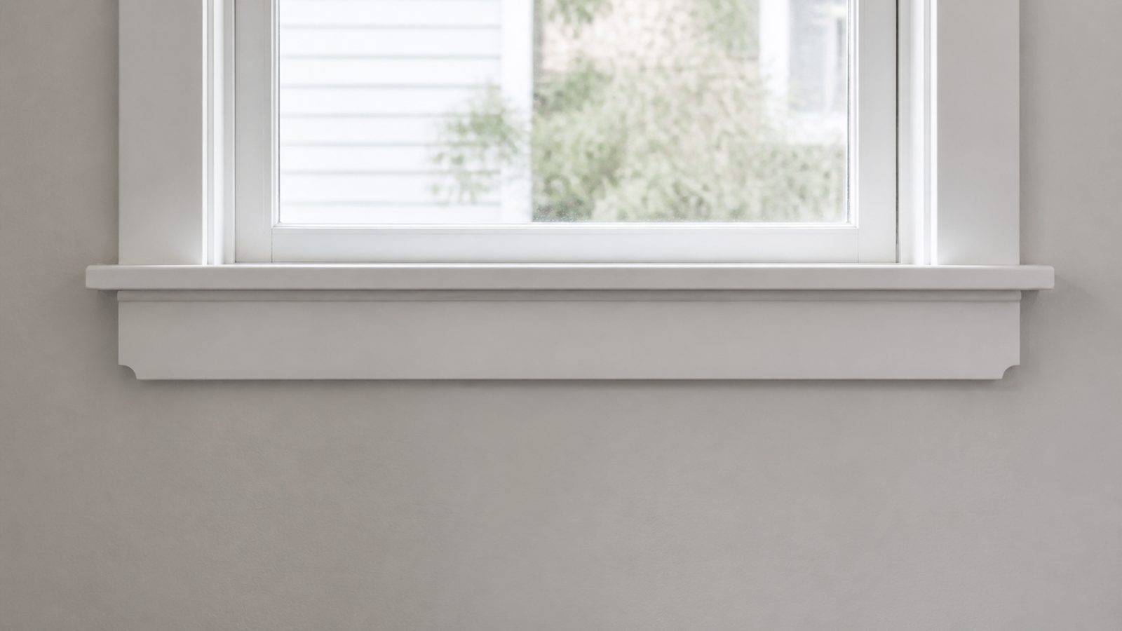 Finished white window stool and fitted apron beneath a residential window